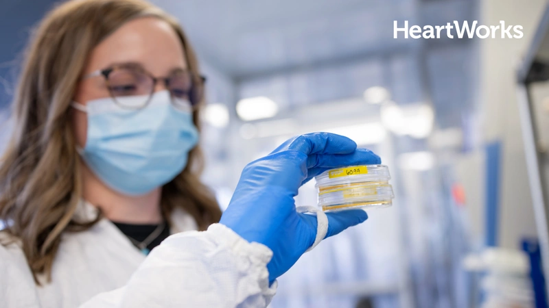scientist looking at lab sample with Heart Works logo
