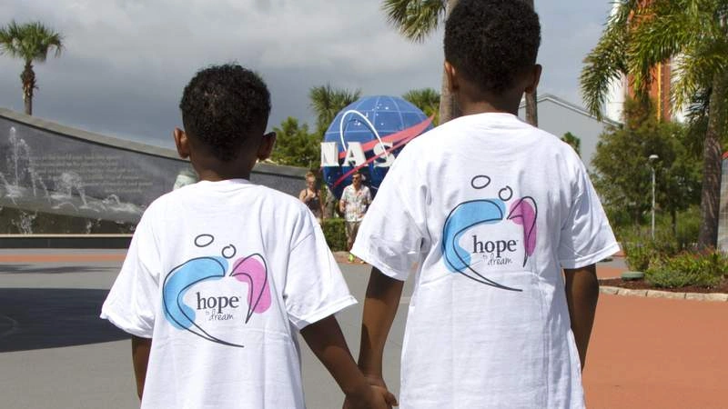 two children holding hands wearing shirts that say hope to dream