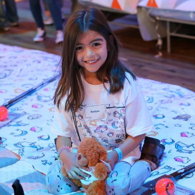 child sitting on a bed with a stuffed animal toy