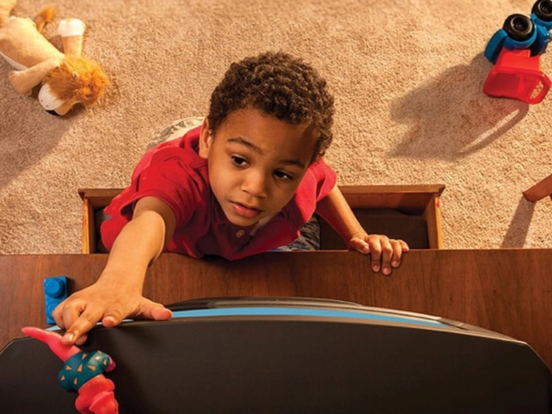 Kid stepping on drawer reaching for toy
