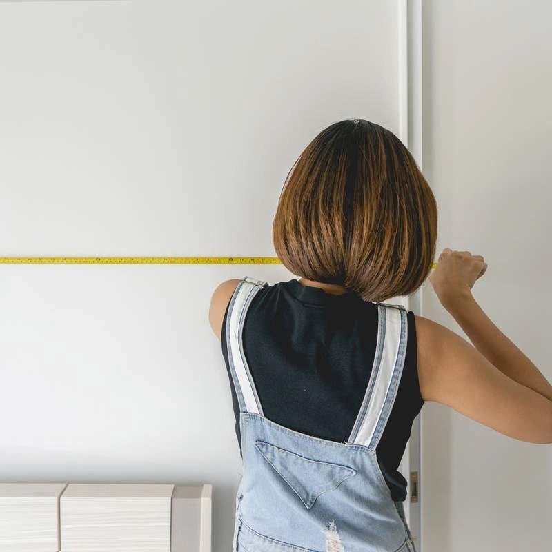 Woman Measuring wall with measuring tape