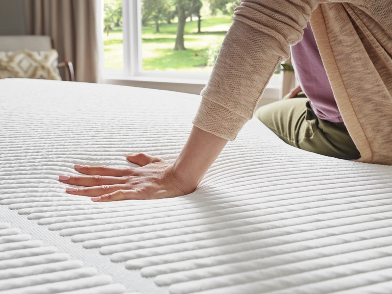 a hand pushing on a mattress