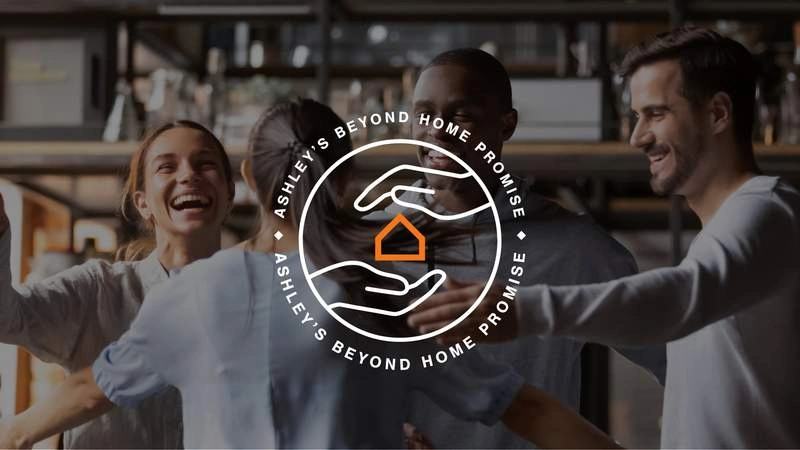 Ashley warehouse employees smiling and celebrating behind an overlay for Ashley's byond home promise log 